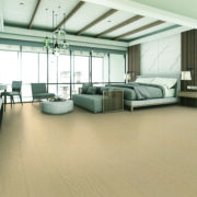 The bedroom is decorated in a modern style with wooden tones with seating and bed and wall decoration. With large windows and high ceilings on parquet floors.