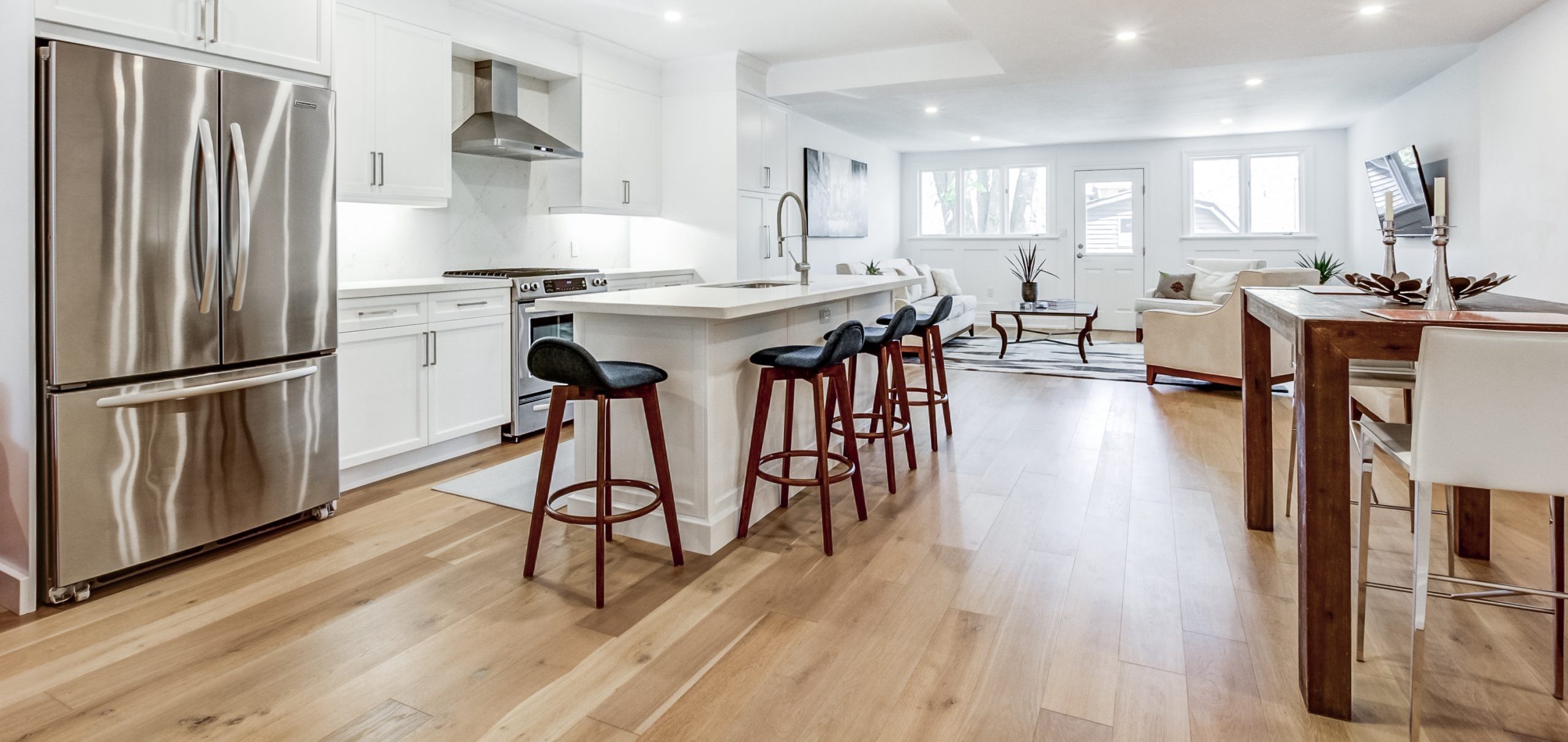 Hardwood flooring running continuously through an open concept kitchen and living area